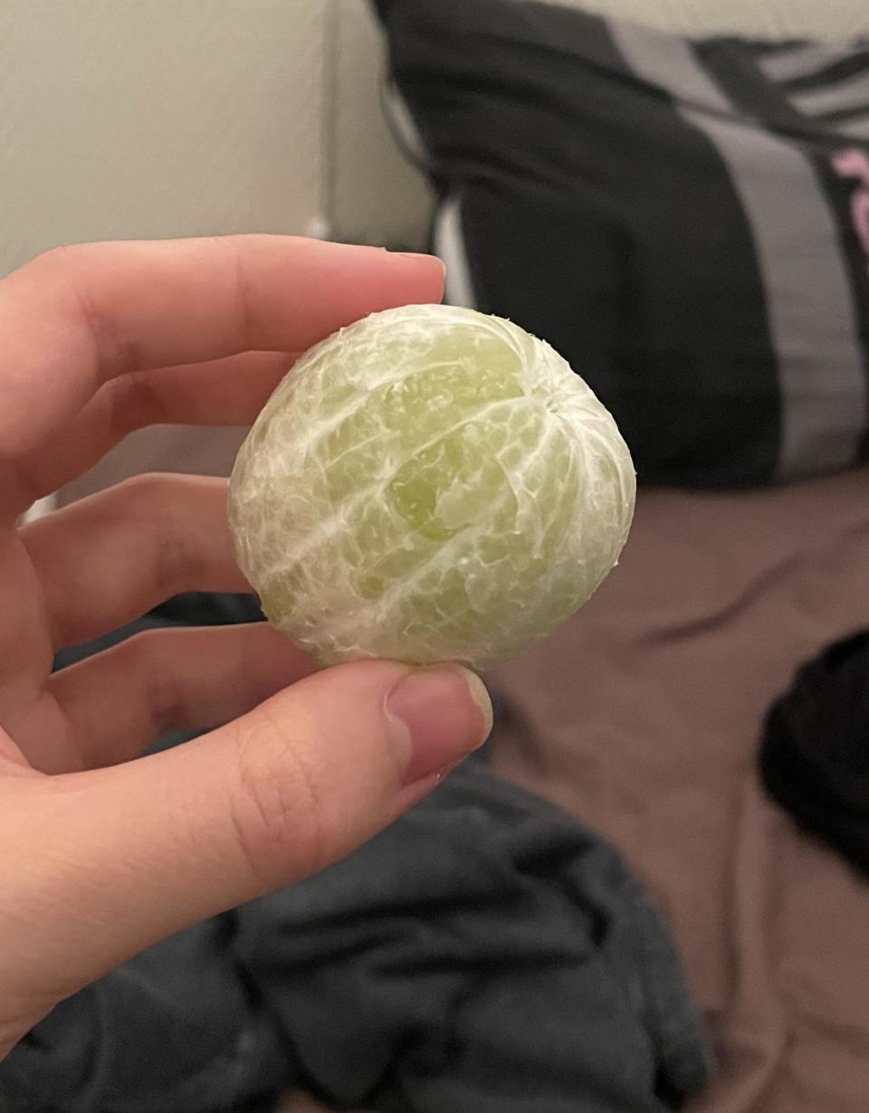 A hand holding a perfectly peeled lime