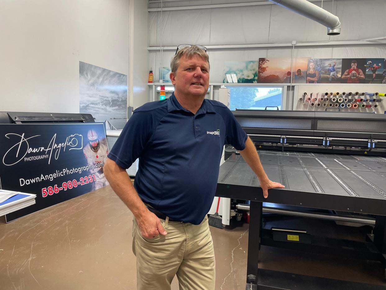 John Nagel leans on an enormous printer at image360 in Genoa Township, Thursday, Sept. 7, 2023.