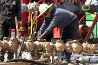 An oil well worker helps to re-plug an abandoned well on the ranch of Ashley Williams Watt, Friday, July 9, 2021, near Crane, Texas. The wells on Watt's property seem to be unplugging themselves. Some are leaking dangerous chemicals into the ground, which are seeping into her cattle's drinking water. And she doesn't know how long it's been going on. (AP Photo/Eric Gay)