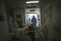 In this Sunday, Feb. 16, 2020, photo, medical workers transfer a new coronavirus patient at a hospital in Wuhan in central China's Hubei province. Chinese authorities on Monday reported a slight upturn in new virus cases and hundred more deaths for a total of thousands since the outbreak began two months ago. (Chinatopix via AP)