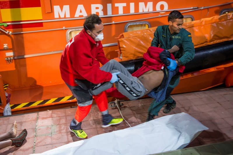 A Spanish coast guard and a member of Spanish Civil Guard carry the body of a migrant, after rescuing dozens of migrants in a raft off the coast at the Mediterranean Sea, at the port of the Spanish North African enclave of Melilla