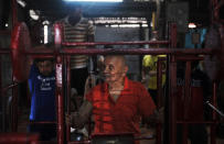 Indian body builder Manohar Aich, on the eve of his 100th birthday, looks on as other young body builders exercise in a gymnasium, in Kolkata on March 16, 2012.