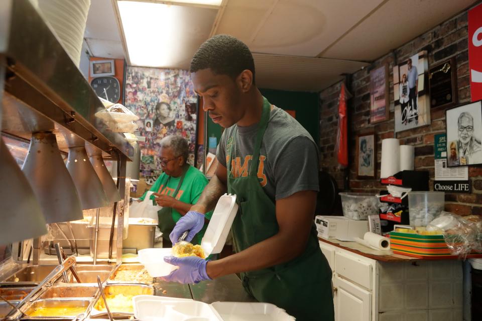 Quasi Roque, an employee at Olean's Cafe, serves food during the lunch rush Wednesday, July 3, 2019. 