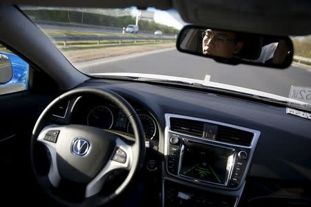 Li Zengwen, a development engineer at Changan Automobile, is reflected in a mirror as a self-driving car from the company is on self-driving mode during a test drive on a highway in Beijing, China, April 16, 2016. REUTERS/Kim Kyung-Hoon