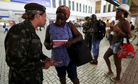 A Brazilian Army soldier distributes pamphlets with information to combat the Aedes aegypti mosquito during the National Day of Mobilization Zika Zero at Central train station in Rio de Janeiro, Brazil, February 13, 2016. REUTERS/Sergio Moraes