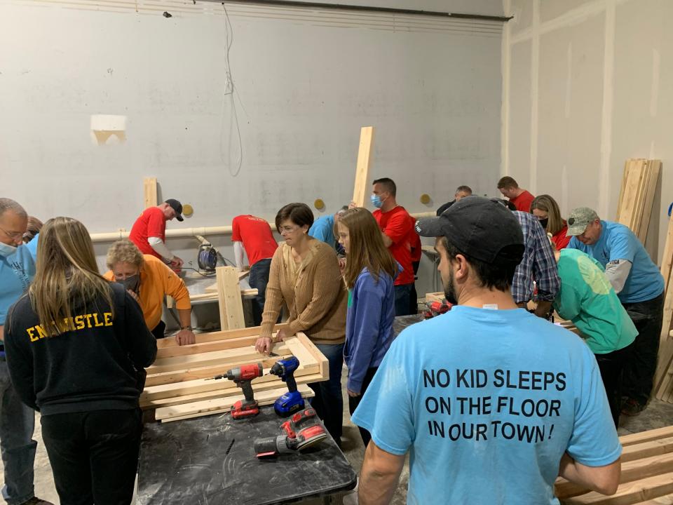 Volunteers for Sleep in Heavenly Peace work to assemble bed frames inside the Sangertown Square mall on Tuesday, Nov. 23, 2021.