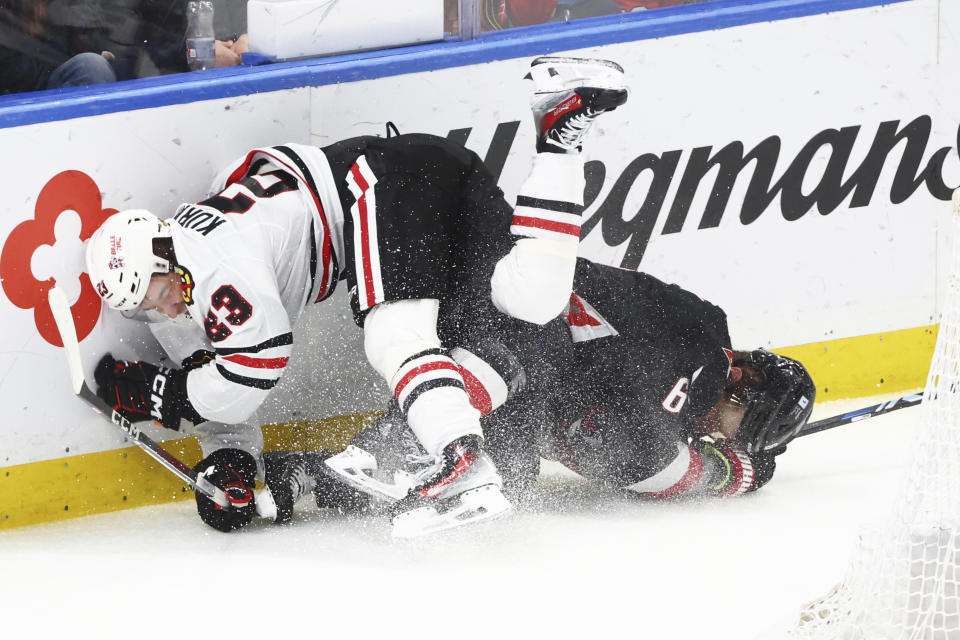 Buffalo Sabres defenseman Erik Johnson (6) is checked from behind by Chicago Blackhawks center Philipp Kurashev (23) during the third period of an NHL hockey game Thursday, Jan. 18, 2024, in Buffalo, N.Y. (AP Photo/Jeffrey T. Barnes)