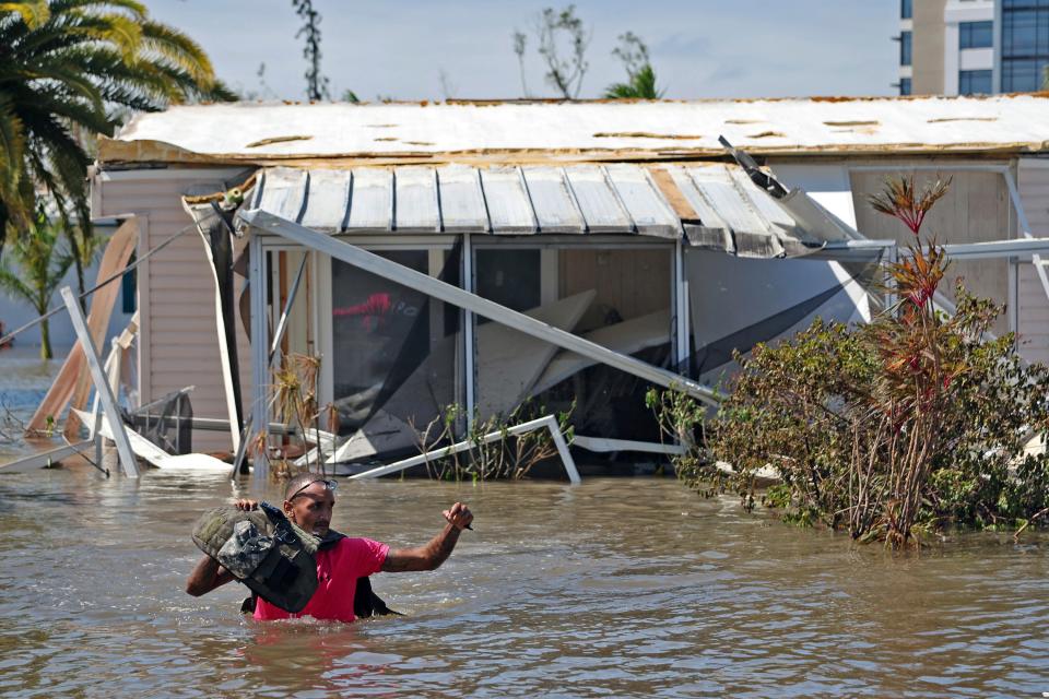 Jonathan Strong holds his vest above the water as he wades through floodwaters while knocking on doors in a flooded mobile home community in Iona, an unincorporated community in Lee County near Fort Myers, Fla., Thursday, Sept. 29, 2022. Strong, who is unaffiliated with any volunteer group, said he came out to help because, "I can't just sit around while my house is intact and let other people suffer. It's what we do; community helping community." Hurricane Ian made landfall Wednesday, Sept. 28, as a Category 4 hurricane on the southwest coast of Florida.