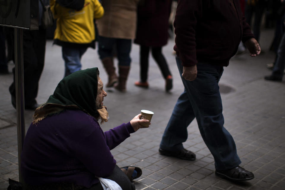 A woman begs for alms in a street in Barcelona.