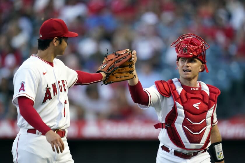 Los Angeles Angels starting pitcher Shohei Ohtani, left, taps gloves with Max Stassi at the end of the top of the second inning of a baseball game against the Seattle Mariners on Monday, Aug. 15, 2022, in Anaheim, Calif. (AP Photo/Marcio Jose Sanchez)