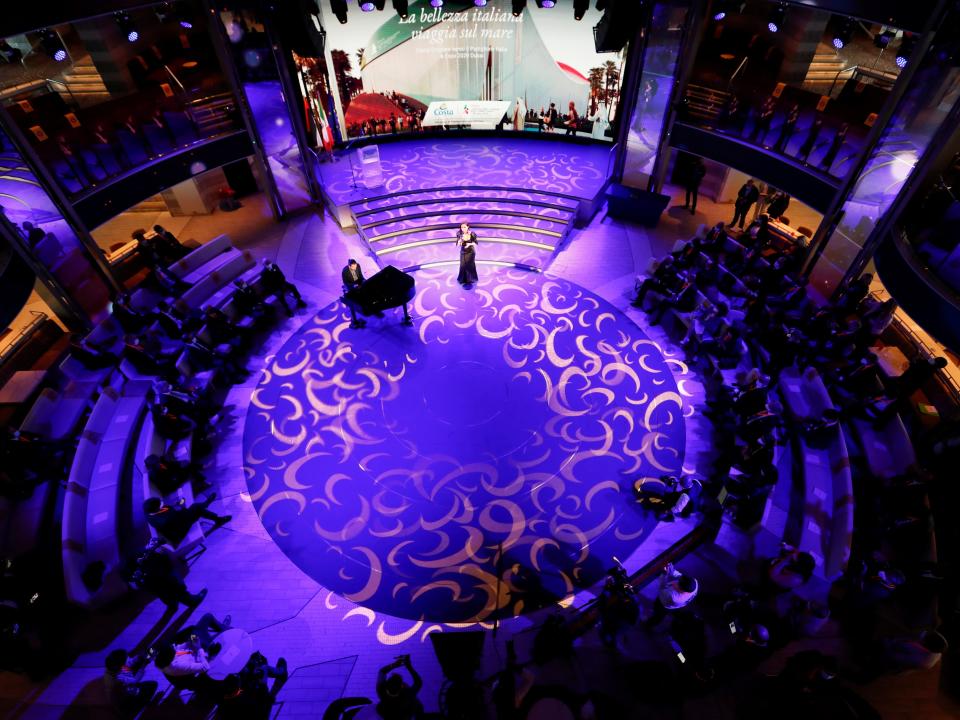 This image looks down on a purple circular stage with a singer standing in the top center and people sitting on the circle's outer rim.