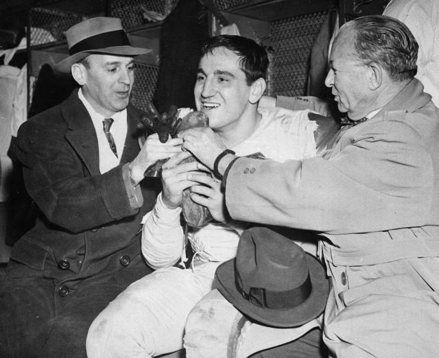 FILE - In this Dec. 8, 1953, file photo, Cleveland Browns coach Paul Brown  checks the protective mask of his quarterback Otto Graham. In 1950, the NFL  merged with the All-America Football