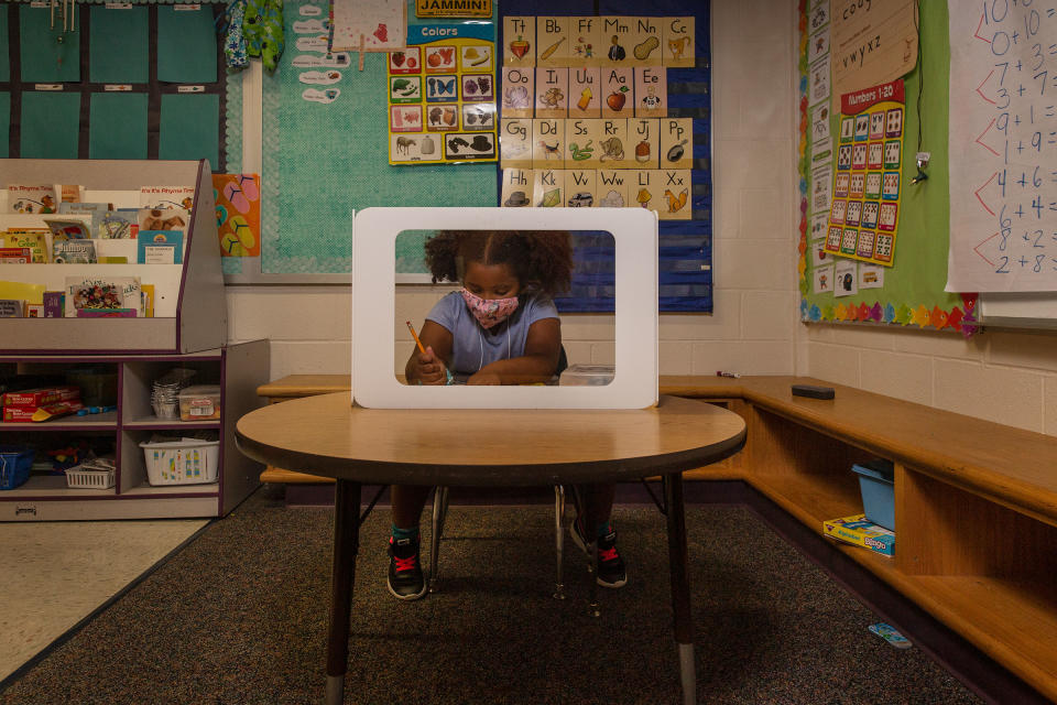 Plastic shields surround the desk where 6-year-old Aven Mullins works | Gillian Laub for TIME