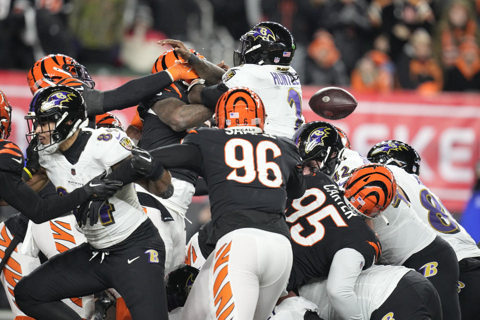 Baltimore Ravens quarterback Tyler Huntley (2) fumbles the ball as it is knocked away by Cincinnati Bengals linebacker Logan Wilson, left, in the second half of an NFL wild-card playoff football game in Cincinnati, Sunday, Jan. 15, 2023. The Bengals' Sam Hubbard recovered the fumble and ran it back for a touchdown. (AP Photo/Darron Cummings)