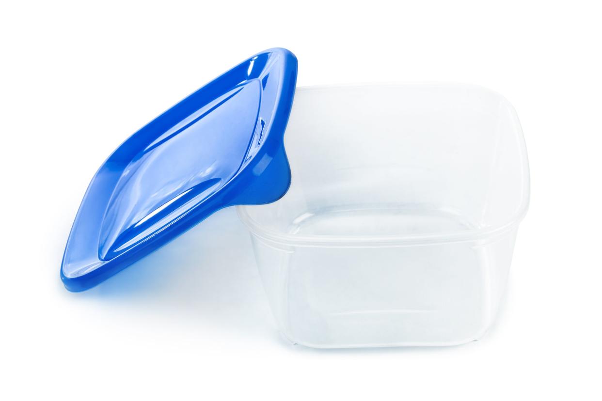 A square plastic food-storage container with a blue lid, opened, on a white background with shadowing