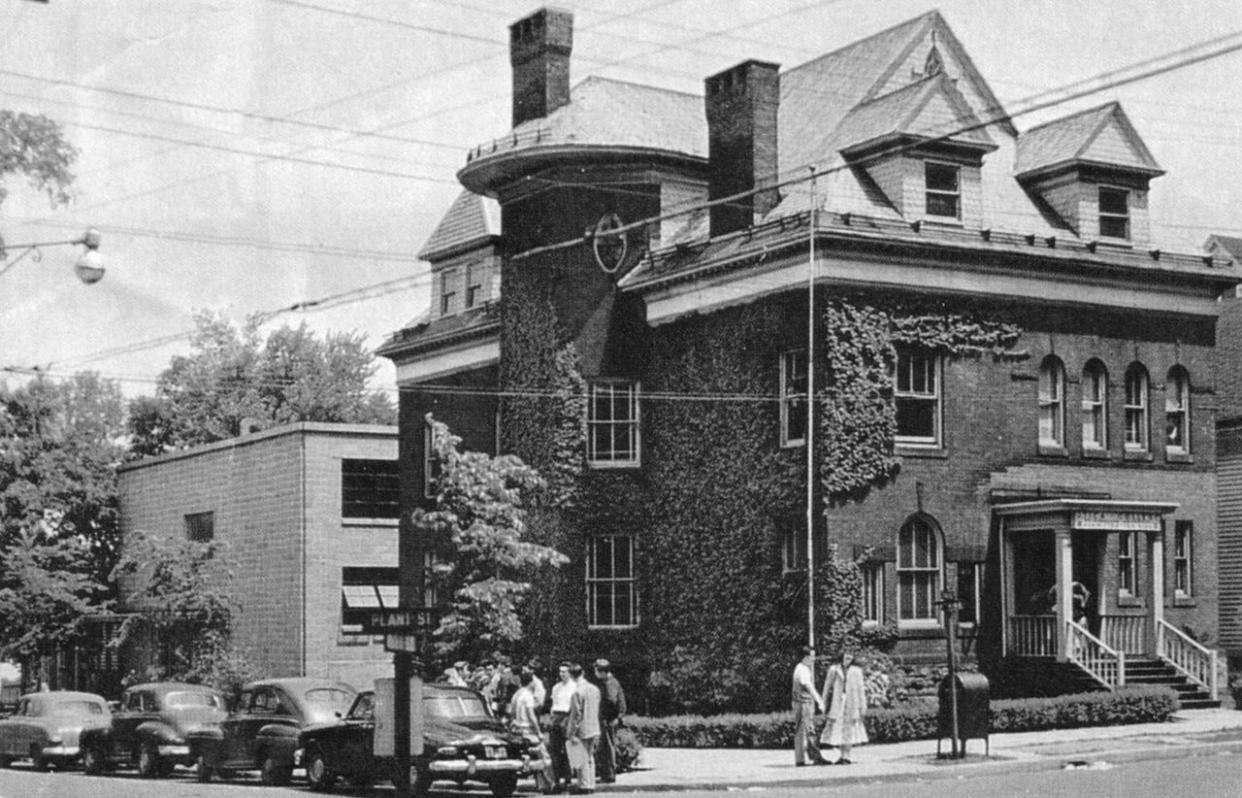 On Sept. 30, 1946, Utica College of Syracuse University (today Utica University) opened for the first time in the vicinity of Oneida Square. Two years later, it purchased this ivy-covered building on the northeast corner of Plant and Hart streets – one block west of the square – and converted it into its administrative building. It remained so until 1961, when the college moved to its new campus on Burrstone Road. The building later was used as a fraternity house by Alpha Phi Delta and eventually was torn down. Today the site is a parking lot.