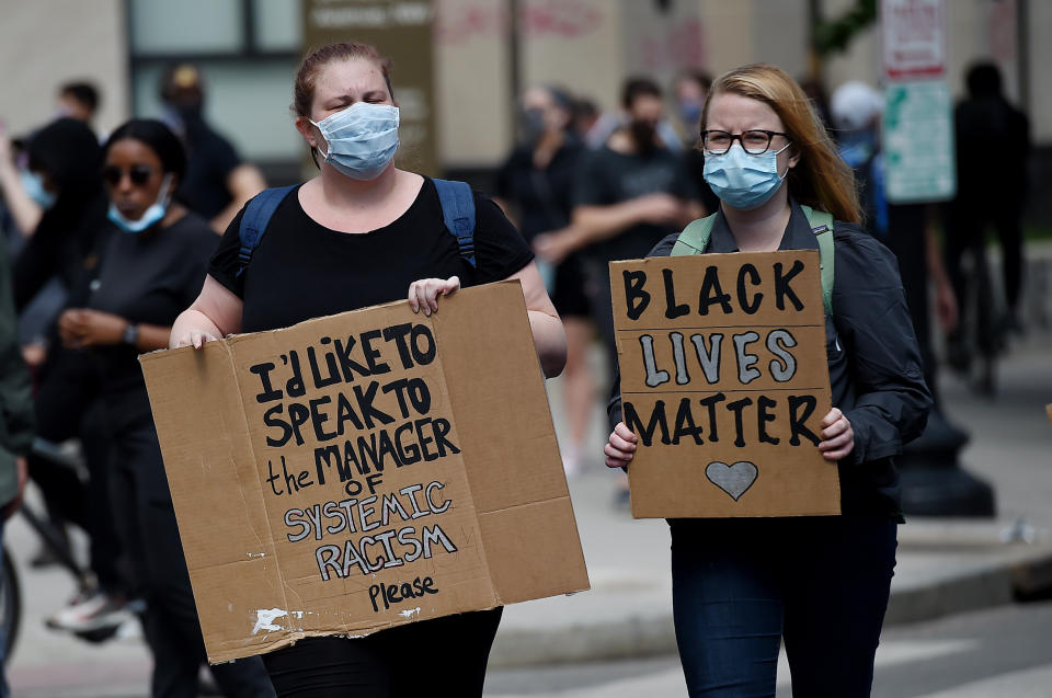 <i>Demonstrators march near Lafayette Park across from the White House on June 2 in Washington, D.C. The sign on the left says, "I'd like to speak to the manager of systemic racism, please." The other reads: "Black Lives Matter."</i>