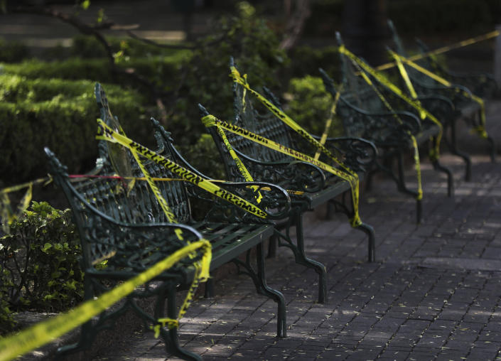 Caution tape is looped around park benches to discourage people from sitting on them in the main plaza of Coyoacan, in Mexico City, Saturday, April 4, 2020. Mexico has started taking tougher measures against the new coronavirus, but some experts warn the country is acting too late and testing too little to prevent the type of crisis unfolding across the border in the United States. (AP Photo/Fernando Llano)