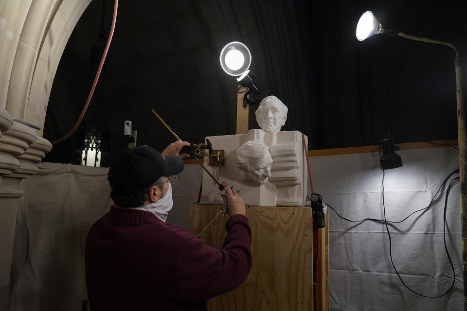 Stone carver Sean Callahan works with a pointing machine on plaster models from a sculpture by Chas Fagan of Holocaust survivor and Nobel Peace Prize winning author Elie Wiesel in the Human Rights Porch at the Washington National Cathedral, Friday, March 12, 2021. The tool is used to accurately copy plaster sculpture models into stone. (AP Photo/Carolyn Kaster)