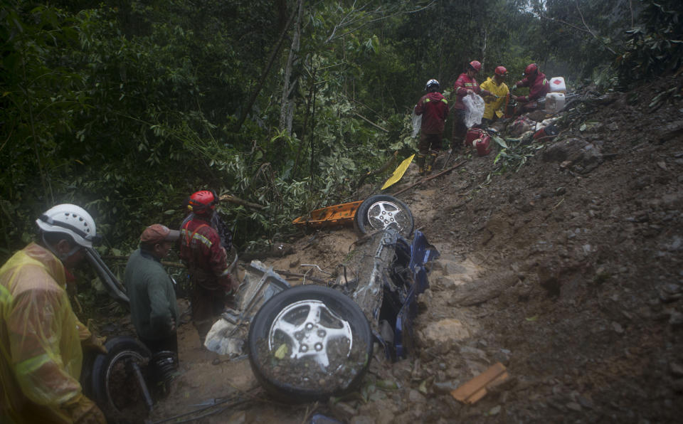 Firefighters look for victims after a mudslide on the outskirts of El Choro, Bolivia, Saturday, Feb. 2, 2019. According to police, at least five people died and others were injured after vehicles were dragged Saturday by a mudslide on a mountainous road in the north of La Paz. (AP Photo/Juan Karita)