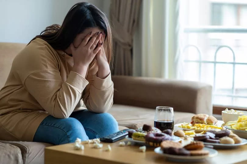 Unhappy stressed woman in in front of a plate of food