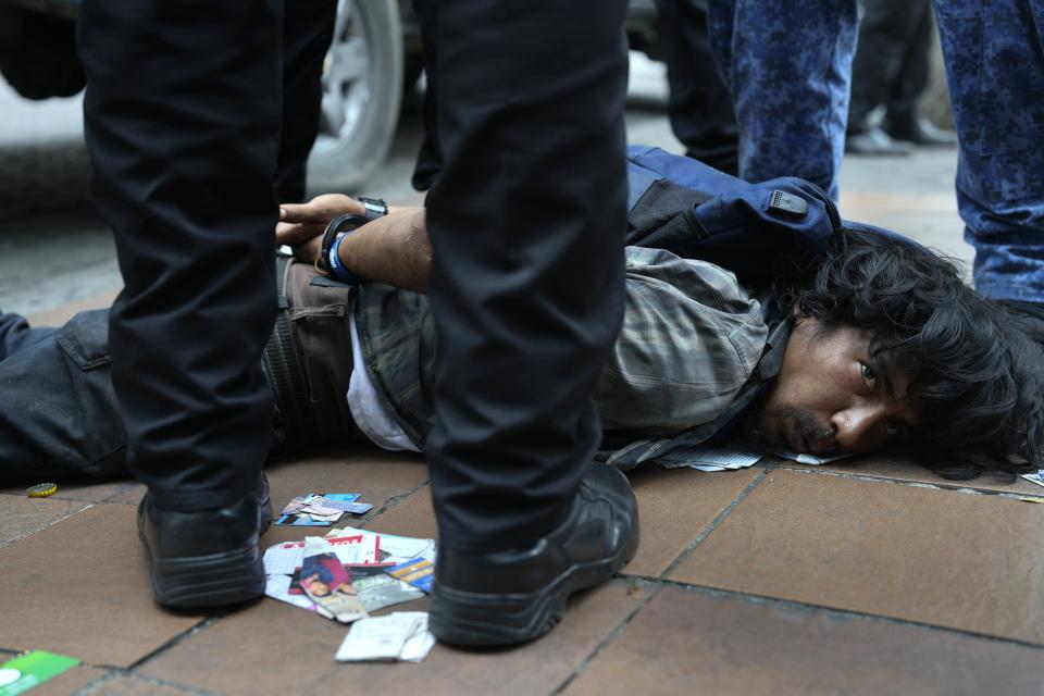 A man is detained in downtown Guayaquil, Ecuador, Friday, Aug. 18, 2023. According to police, the detainee injured the neck of a lottery salesman with a piece of a broken bottle, in an attempted robbery. (AP Photo/Martin Mejia)