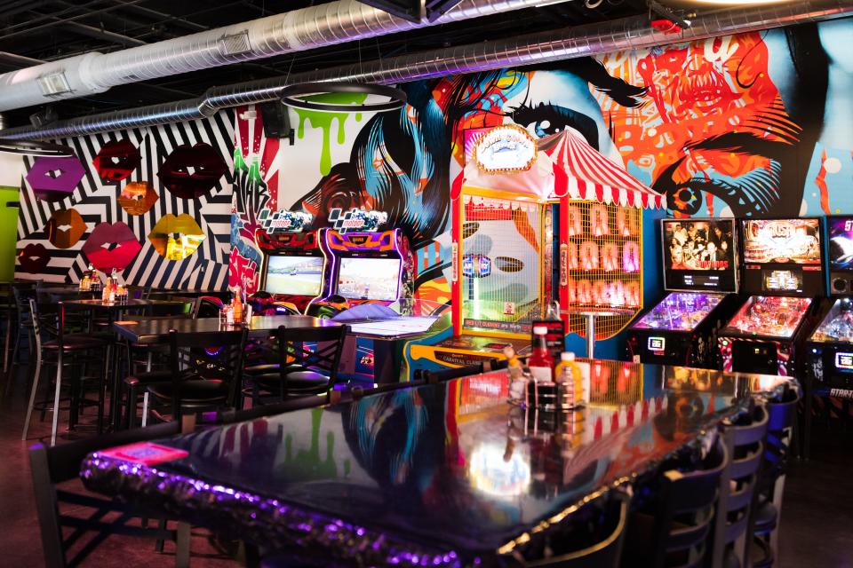 The seating area, colorful mural, and arcade games lining the walls at Carousel Arcade Bar in Westgate.