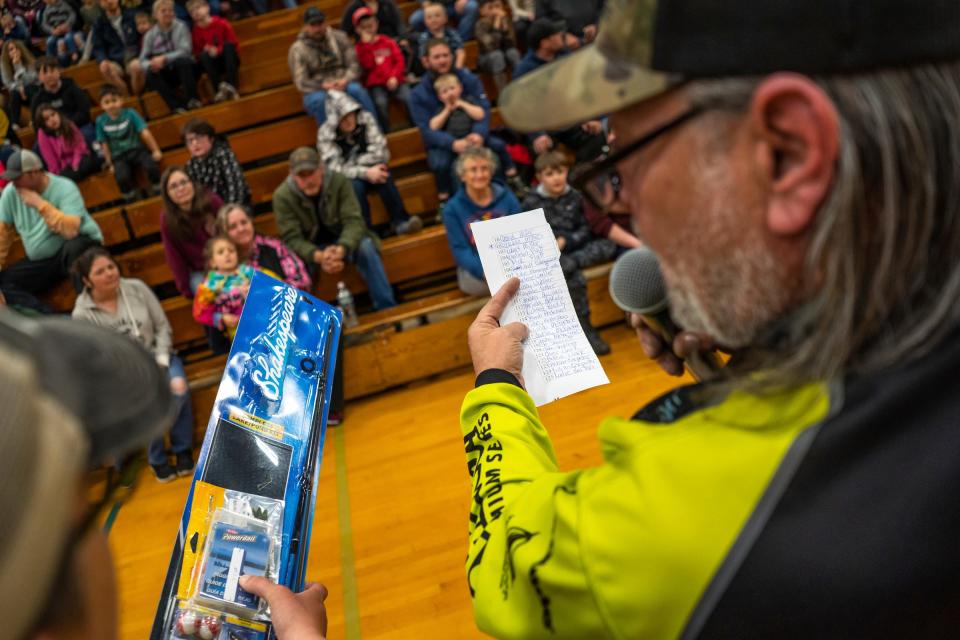 Local DJ and fishing champion Casey Cook, of Newberry, right, reads the names of winners to a crowd gathered during the 65th annual Kids Tackle Party held by the Tahquamenon Sportsmen's Club at Newberry High School in Newberry on Saturday, April 22, 2023, in Michigan's Upper Peninsula.