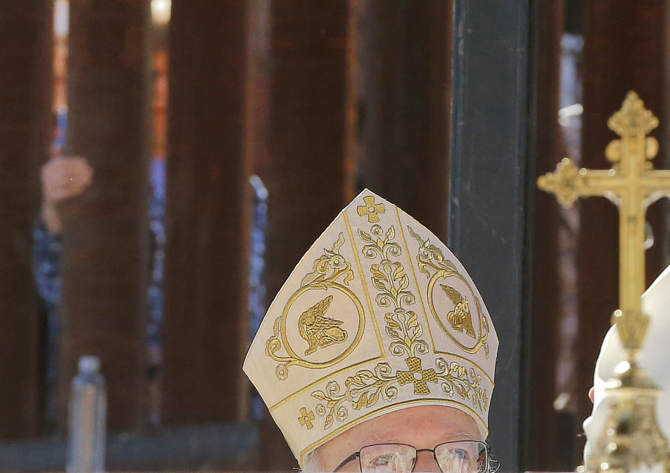 Cardinal Sean O'Malley peers over the communion table as he leads mass, Tuesday, April 1, 2014, along the international border wall in Nogales, Ariz. A delegation of Roman Catholic leaders celebrated Mass along the U.S.-Mexico border to raise awareness about immigration and to pray for policy changes. (AP Photo/Matt York)