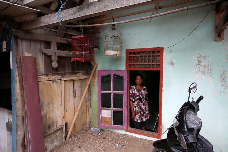 Fisherman Miskan's wife Faridah, 37, stands by a window which has been repurposed into a door for their house, affected by land subsidence, at Tambaklorok village in Semarang