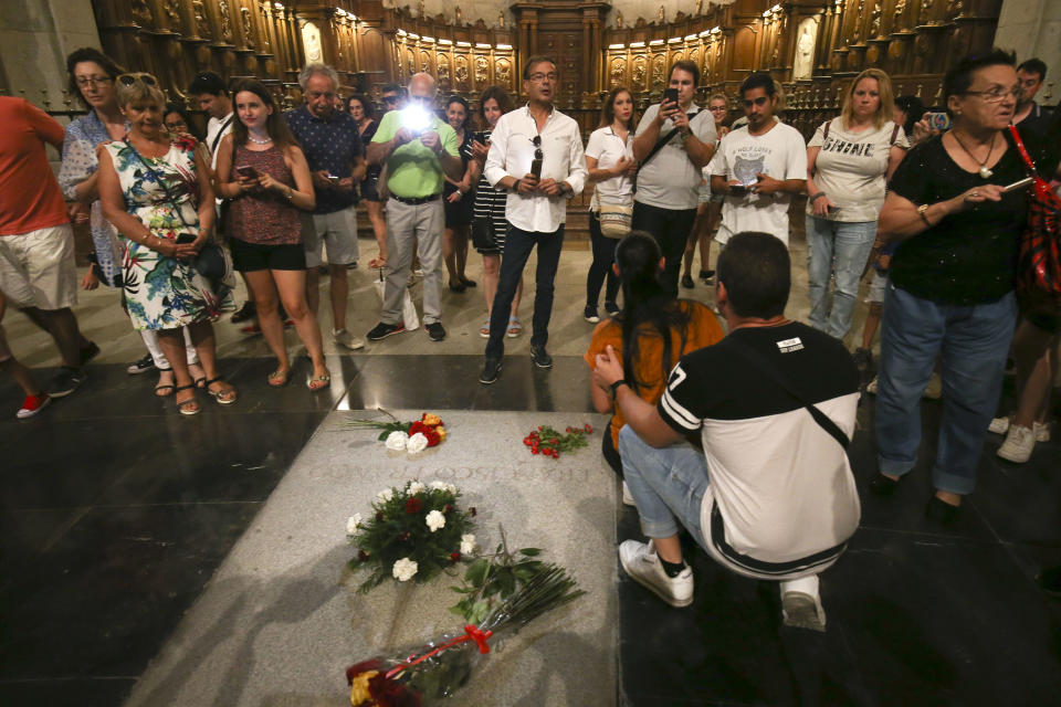 People stand around the tomb of former Spanish dictator Francisco Franco inside the basilica at the the Valley of the Fallen monument near El Escorial, outside Madrid on Friday, Aug. 24, 2018. Spain's center-left government has approved legal amendments that it says will ensure the remains of former dictator Gen. Francisco Franco can soon be dug up and removed from a controversial mausoleum. (AP Photo/Andrea Comas)
