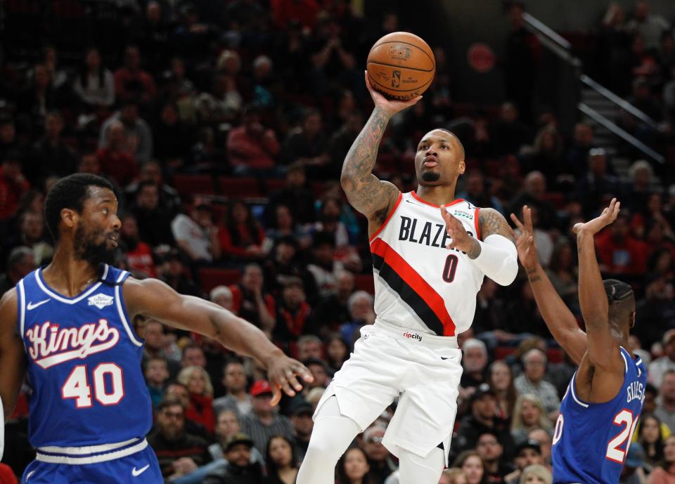 Portland Trail Blazers guard Damian Lillard, center, shoots as Sacramento Kings forward Harrison Barnes, left, and forward Harry Giles III, right, defend during the first half of an NBA basketball game in Portland, Ore., Saturday, March 7, 2020. (AP Photo/Steve Dipaola)