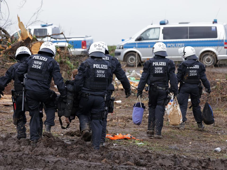 ERKELENZ, GERMANY - JANUARY 13: Police in riot gear carry away an activist out of the settlement of Luetzerath on January 13, 2023 near Erkelenz, Germany. Police have been evicting environmental activists who have occupied the abandoned Luetzerath settlement and who are seeking to prevent Luetzerath's demolition that will make way for an expansion of the adjacent Garzweiler II open cast coal mine. Of the several hundred activists on site approximately a few dozen remain, some in a house and others in tree houses or attached to poles. The North Rhine-Westphalia state government of German Christian Democrats (CDU) and Greens has approved the demolition and the coal mine expansion, while at the same time announcing an accelerated phase out of coal-fired energy production in the state from 2028 to 2030. Other nearby settlements that were also slated for demolition will now be spared, though critics point out that Germany has sufficient energy production capacity and does not need the coal lying beneath Luetzerath. (Photo by Sean Gallup/Getty Images)