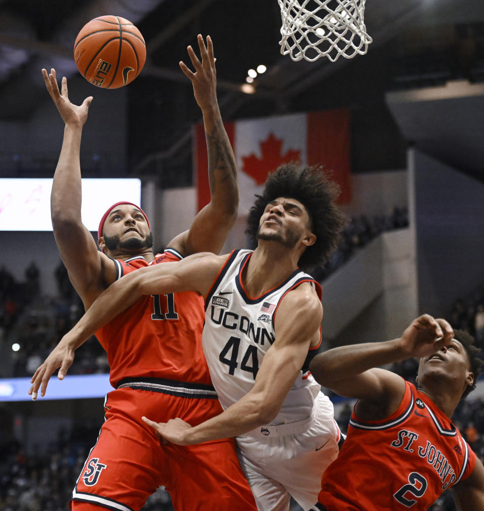 St. John's Joel Soriano (11) reaches for a rebound against UConn's Andre Jackson Jr. (44) as St. John's AJ Storr (2) defends in the first half of an NCAA college basketball game, Sunday, Jan. 15, 2023, in Hartford, Conn. (AP Photo/Jessica Hill)