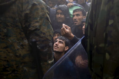 Migrants and refugees beg Macedonian policemen to allow passage to cross the border from Greece into Macedonia during a rainstorm, near the Greek village of Idomeni, September 10, 2015. REUTERS/Yannis Behrakis