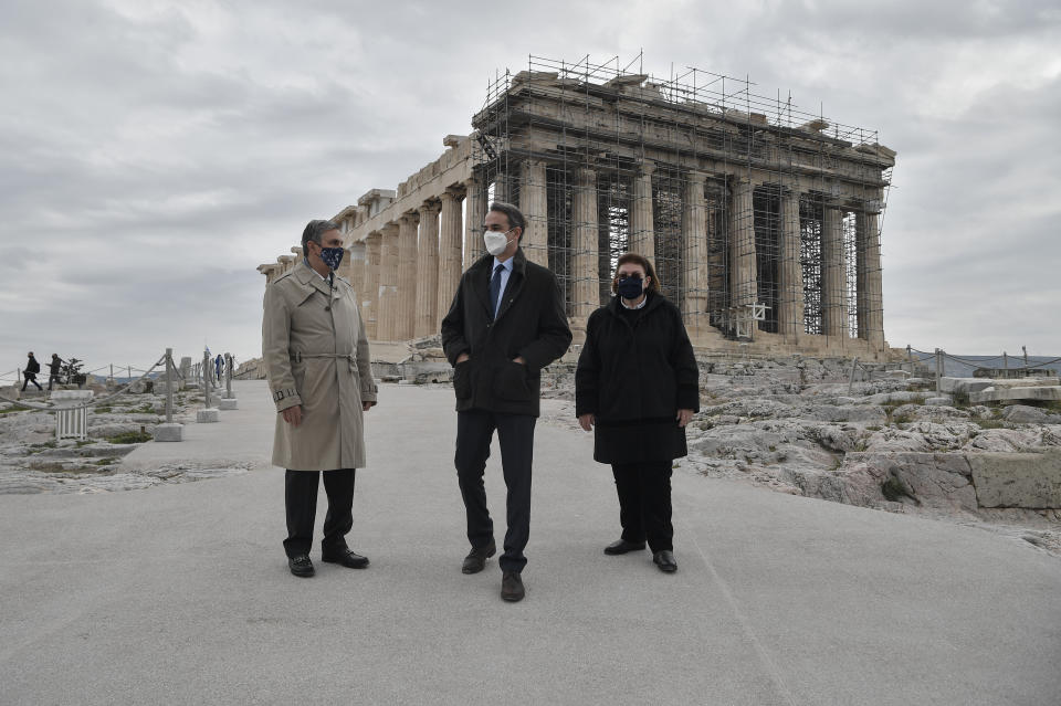 Greek Prime Minister Kyriakos Mitsotakis, center, Culture Minister Lina Mendoni, right, and President of the Onassis Foundation, Antonis Papadimitriou, stand in front of the of the Parthenon Temple, following the restoration of the Acropolis archaeological site in order to become fully accessible to people with disabilities and mobility issues, during the International Day of Persons with Disabilities, in Athens, on Thursday, Dec. 3, 2020. (Louisa Gouliamaki/Pool via AP)