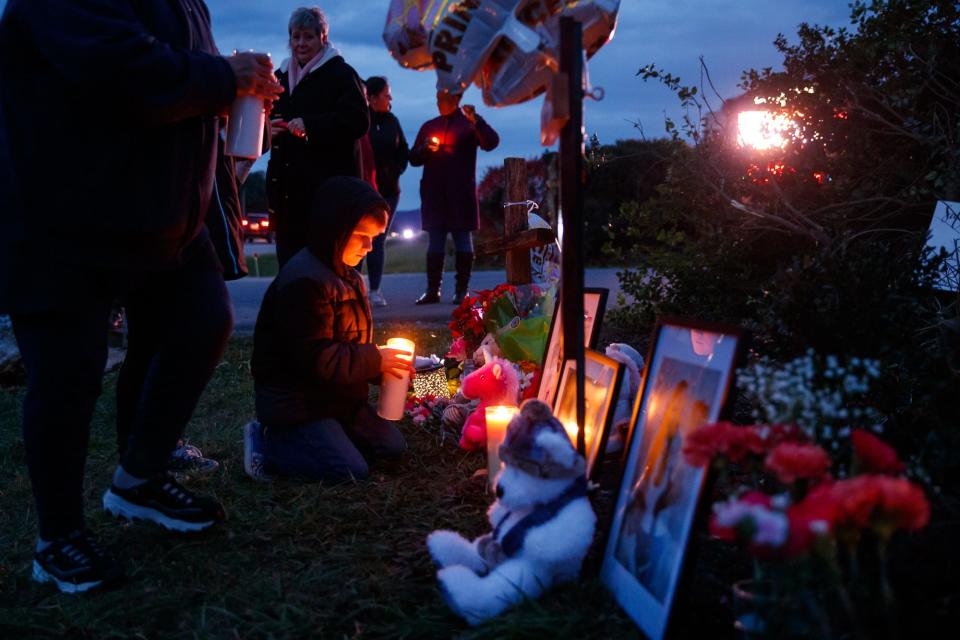 A boy places a candle on a memorial at a candlelight vigil on Sunday, Nov. 21, 2021, for Giana, 7, and Aaminah Vicosa, 6, at the site where the sisters were killed in a murder-suicide by their father, Robert Vicosa, in the 23000 block of Ringgold Pike on Nov. 18, near Smithsburg, Maryland.