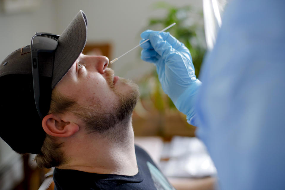 FILE - In this April 21, 2020, file photo, BFAIR shared living home staff member Matthew Donahue receives a COVID-19 swab test in Pittsfield, Mass. At a cost of $120-130 per test, and NHL Commissioner Gary Bettman’s estimate the league will need 25,000-35,000 in total to get through the playoffs, the price tag he concedes is “millions of dollars.” But regular testing is something players insisted on in the name of feeling safe to compete. (Stephanie Zollshan/The Berkshire Eagle via AP, File)