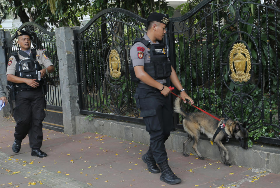 Police officers lead a sniffer dog as they patrol around the General Election Commission office one day after the election in Jakarta, Indonesia, Thursday, April 18, 2019. Indonesia's top security minister and its military and police chiefs said Thursday that they will crack down decisively on any attempts to disrupt public order while official results from presidential and legislative elections are tabulated. (AP Photo/Tatan Syuflana)