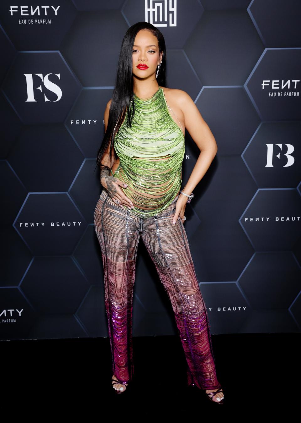 Rihanna in a strappy, green and purple ombre shirt and pant ensemble.