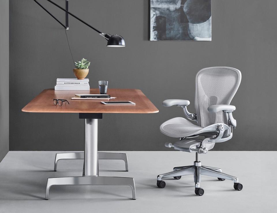 Grey ergonomic chair beside modern wood and steel desk.