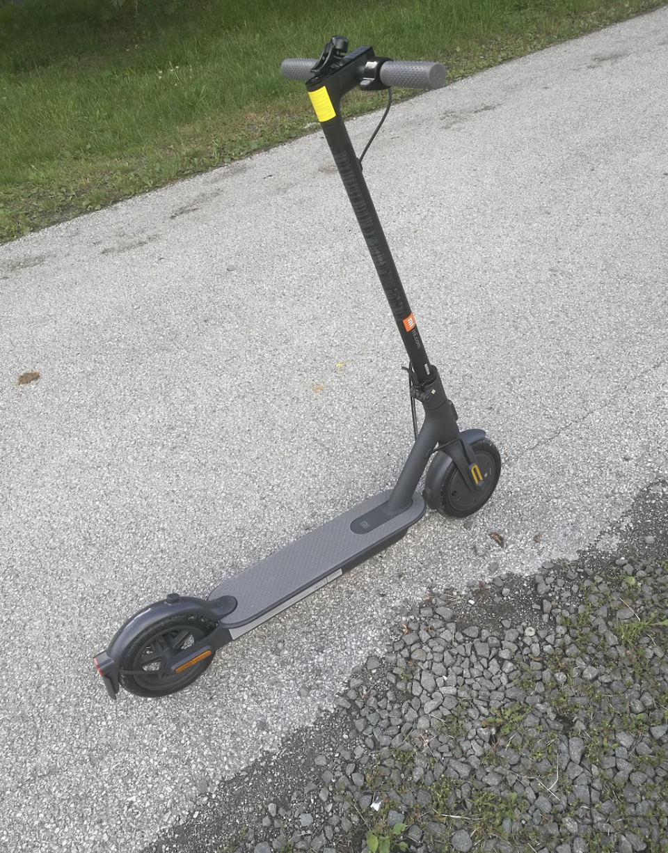 An electric scooter is parked on a paved pathway with grass nearby