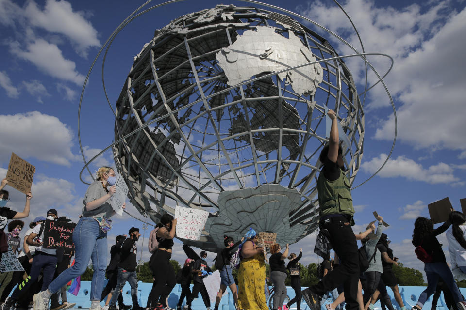 Protesters march around a large sculpture of a globe in Flushing Meadows Corona Park in the Queens borough of New York, Sunday, May 31, 2020. Demonstrators took to the streets of New York City to protest the death of George Floyd, a black man who was killed in police custody in Minneapolis on May 25. (AP Photo/Seth Wenig)