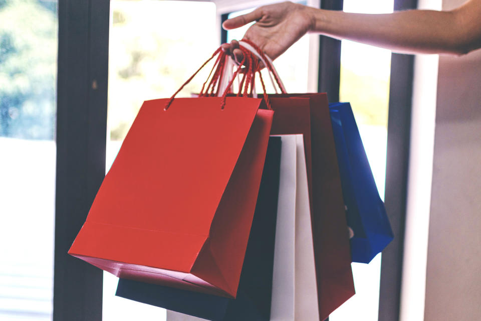 Person holding several shopping bags while standing in a store