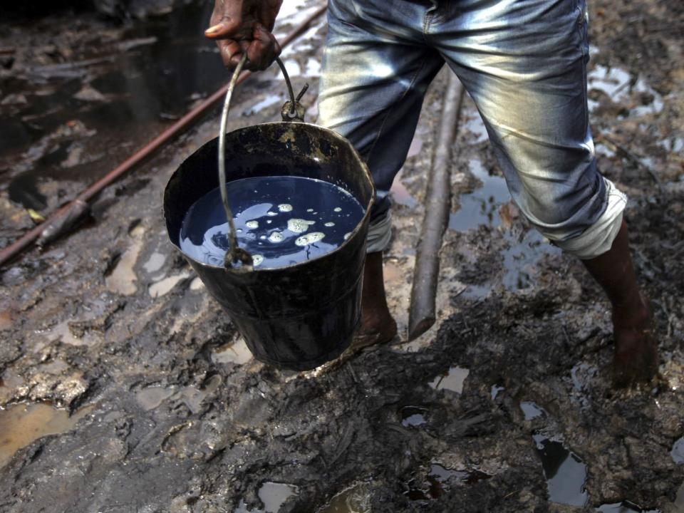 A man carries a bucket of crude oil in Nigeria