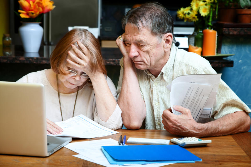 Older man and woman looking at documents worriedly.