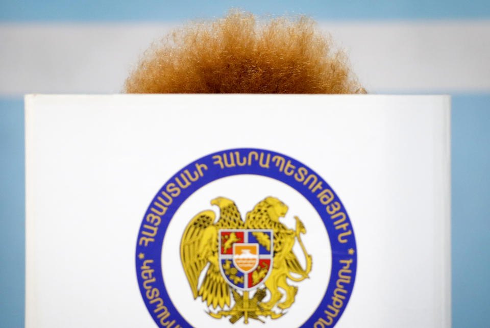 An Armenian woman reads her ballot papers at a polling station during a parliamentary election in Yerevan, Armenia, Sunday, June 20, 2021. Armenians are voting in a national election after months of tensions over last year's defeat in fighting against Azerbaijan over the separatist region of Nagorno-Karabakh. (AP Photo/Sergei Grits)