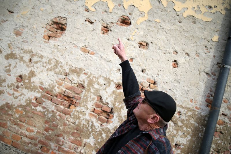 War veteran Rizo Salkic shows bullet holes on a house destroyed during the Bosnian War in Maglaj