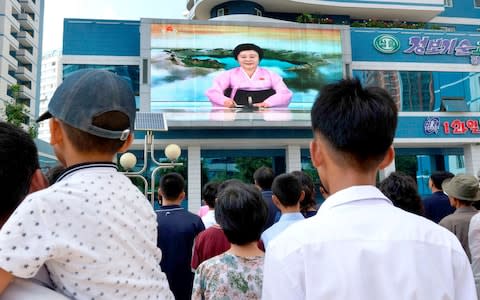 North Koreans watch a news report showing North Korea's nuclear test on electronic screen in Pyongyang - Credit: KYODO/Reuters