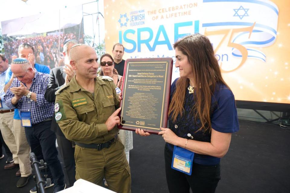 El coronel Golan Vach, quien dirige la famosa Unidad Nacional de Rescate de las Fuerzas de Defensa Israelíes, recibe una placa de manos de Elise Scheck Bonwitt, quien perdió a su familia en la tragedia de Surfside.